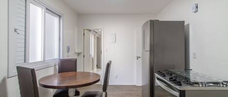 A compact kitchen with a refrigerator, stove, and dining area with chairs and a table.