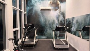 Un gimnasio con cintas de correr y un equipo de aire acondicionado en la pared.