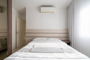 A hotel room with a bed, a bedside table, an air conditioning unit, and a door. - Apt in BC 4min fr th Beach and Av Atlantica Epf202 (Balneário Camboriú)