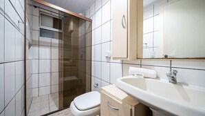 Un bagno con doccia vetrata, un water, un lavandino e uno specchio.