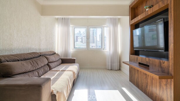Un soggiorno moderno con un divano, una TV a schermo piatto e una finestra con tende.