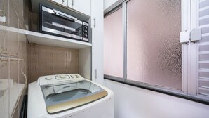 A laundry area with a washing machine and dryer, a window with a textured blind, and a tiled backsplash. - Apt in BC 4min fr th Beach and Av Atlantica Epf202 (Balneário Camboriú)