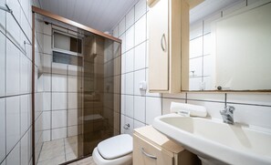 Ein Badezimmer mit Duschkabine, Toilette, Waschbecken und Spiegel.
