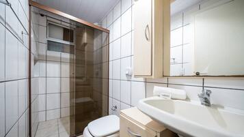 A bathroom with a glass-enclosed shower, a toilet, a sink, and a mirror.