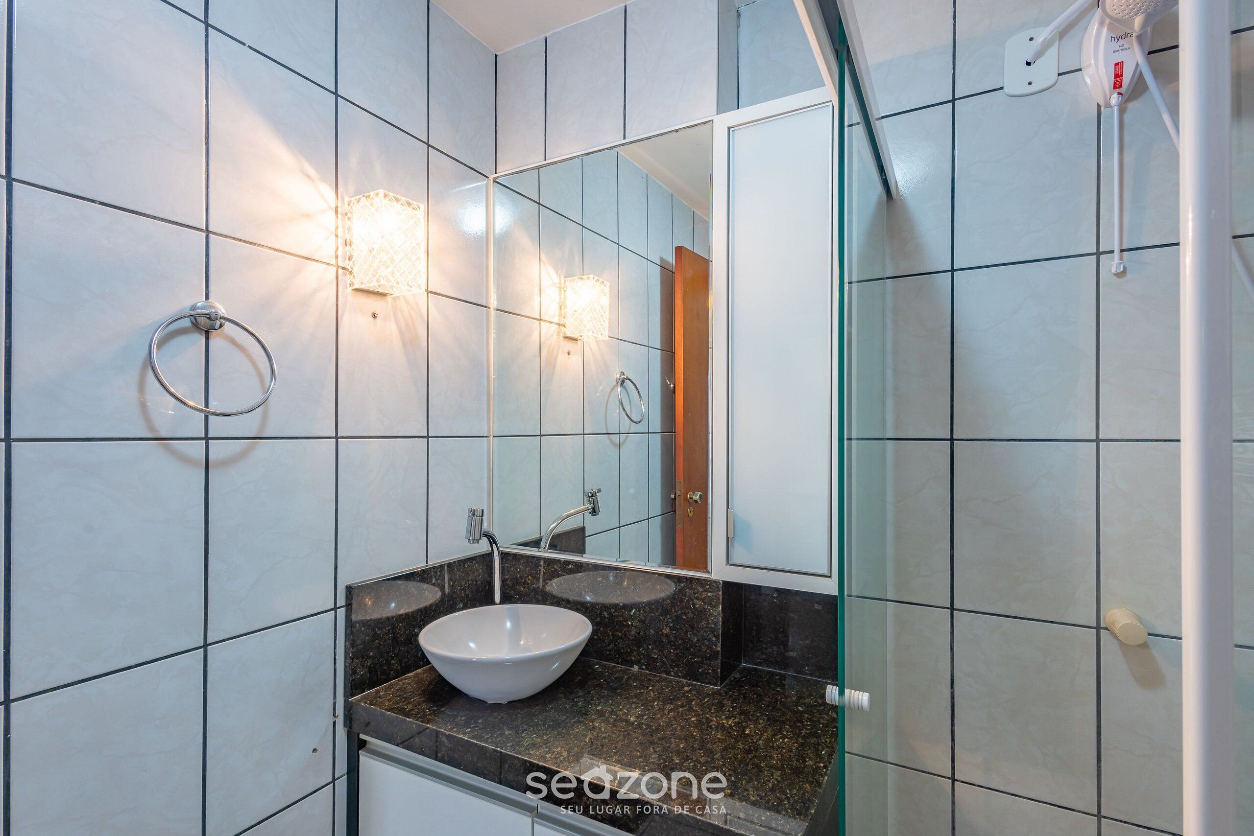 Un bagno con lavandino, specchio e portascopino.