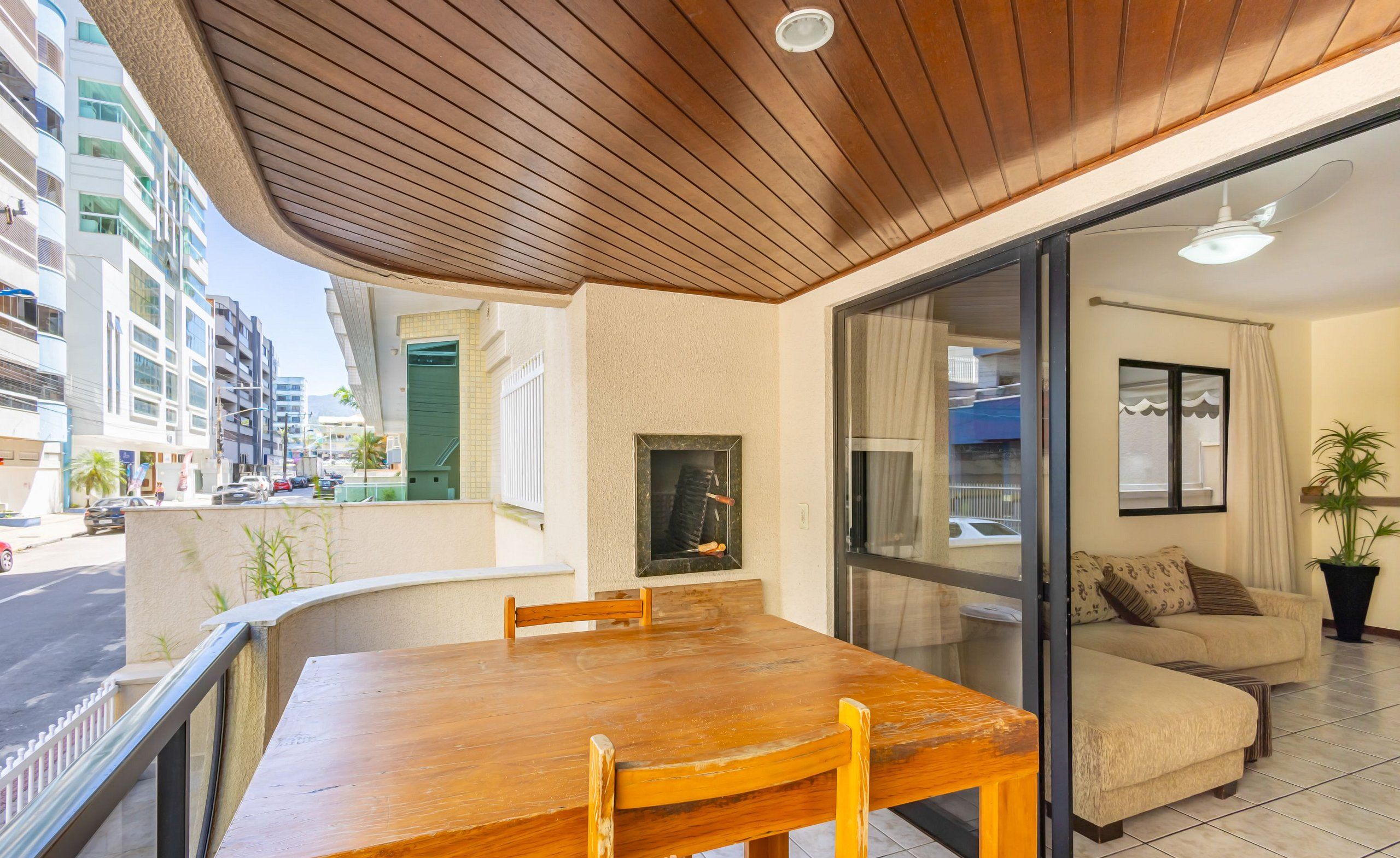 A modern living room with a wooden dining table, a sofa, and a large window.