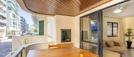 A modern living room with a wooden dining table, a sofa, and a large window.