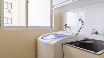 Une buanderie équipée d’un lave-linge, d’un évier et d’une fenêtre.