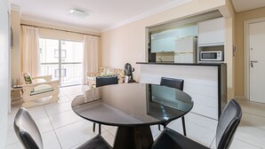 A modern living room with a round dining table, black chairs, a sofa, and a kitchen area with a microwave. - Sea View apt 130m From the Beach in BC Erg605 (Balneário Camboriú)