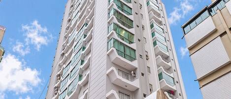Un edificio de varios pisos con un diseño arquitectónico moderno, que cuenta con balcones y ventanas amplias.