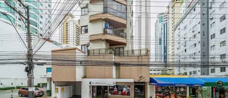 Un edificio de varios pisos con una tienda en la planta baja y un toldo azul.