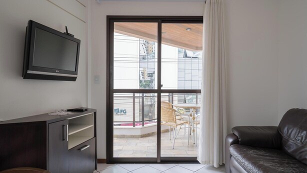 Un salon comprenant un téléviseur, un canapé, un meuble et une porte-fenêtre coulissante donnant sur un espace extérieur aménagé pour se détendre.