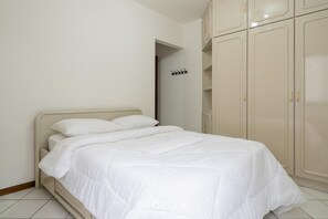 A neatly made bed in a room with white walls and a beige wardrobe. - Apartment w Balcony 250m From Praia Central Erj101 (Balneário Camboriú)