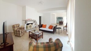 Un salon comprenant un canapé, des fauteuils, une table basse et un téléviseur.