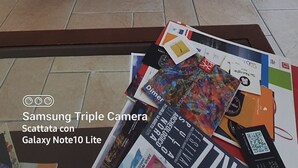 Un salon avec un canapé, une table basse sur laquelle sont posés des magazines, et une cuisine en arrière-plan.