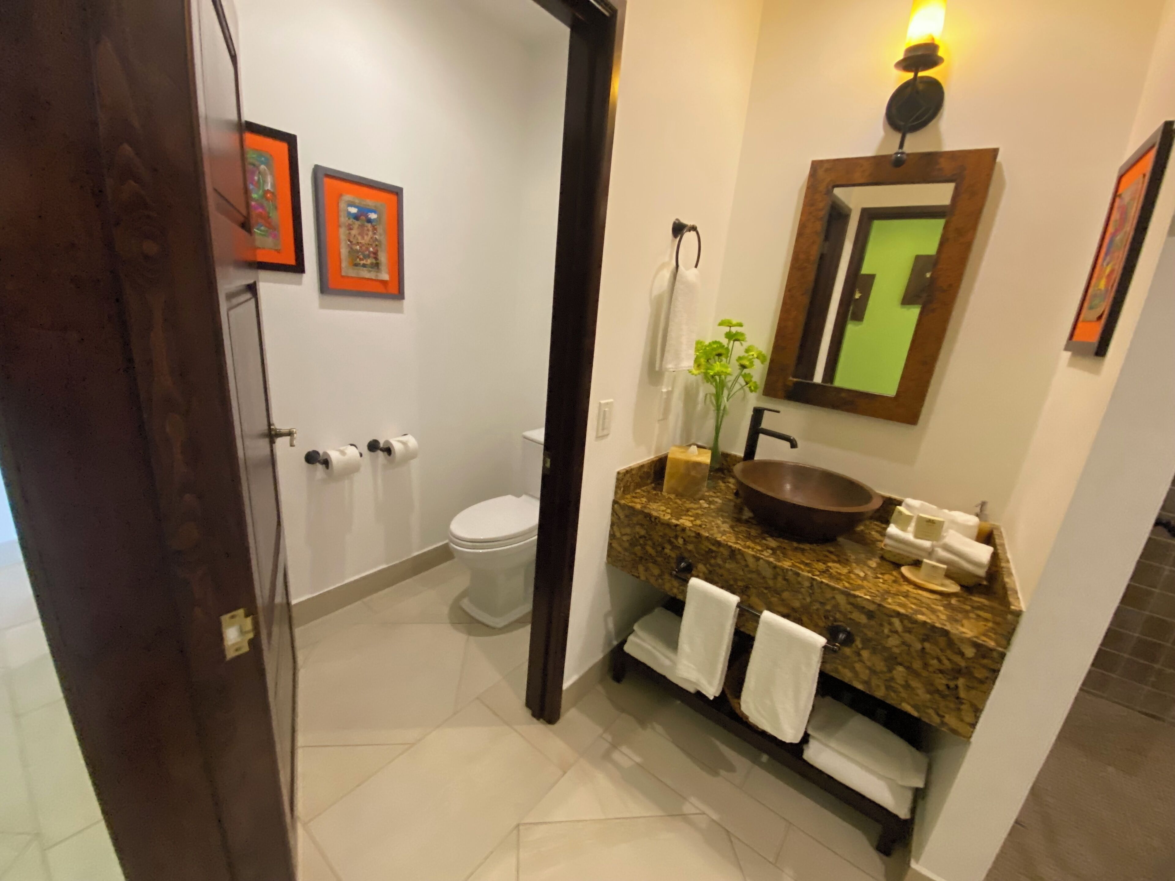 Une salle de bain avec un lavabo en marbre, un grand miroir et des toilettes.