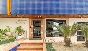 A building with a blue tiled facade, a sign reading "Residencial Valdeli 814", and a well-maintained entrance with steps and potted plants. - Apartment with barbecue, 3 bedrooms ERV0101 (Balneário Camboriú)