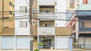 A two-story building with a ground-level entrance and a visible balcony. - Apartment in BC Center With Side sea View Erz0502 (Balneário Camboriú)