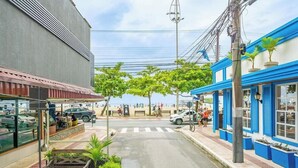 A street view with a café, a blue building with windows, and a pedestrian crossing. - Apartment in BC Center With Side sea View Erz0502 (Balneário Camboriú)