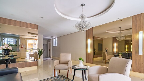 Un hall d’hôtel moderne comprenant un comptoir d’accueil, un espace salon et un grand miroir qui reflète l’ensemble de la pièce.