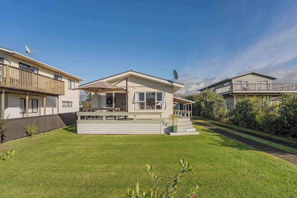 Une maison à deux étages dotée d’un balcon, d’une terrasse couverte et d’une pelouse bien entretenue.