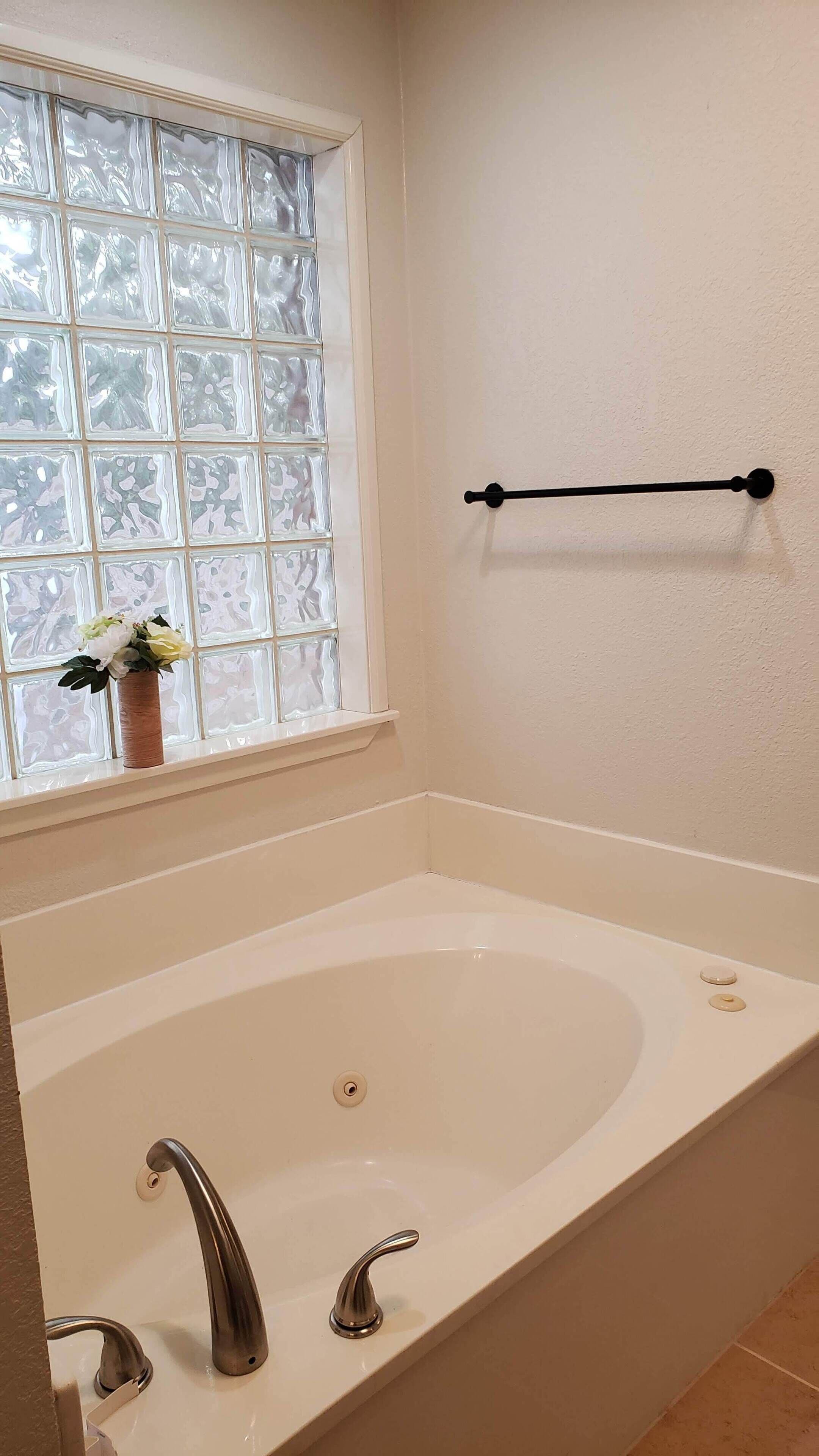 Ein Badezimmer mit Badewanne, einem Fenster mit Milchglas und einem Handtuchhalter.