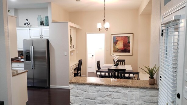 A modern kitchen with a built-in refrigerator, granite countertops, and a stone accent wall.
