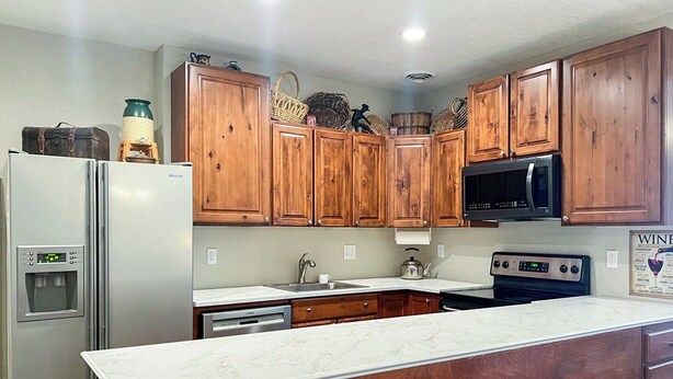 A kitchen with wooden cabinets, a stainless steel refrigerator, a microwave, and a built-in oven.