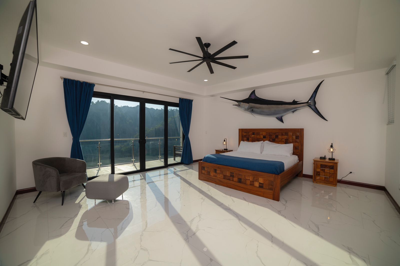 A bedroom with a large bed, a chair, a nightstand, and a ceiling fan.