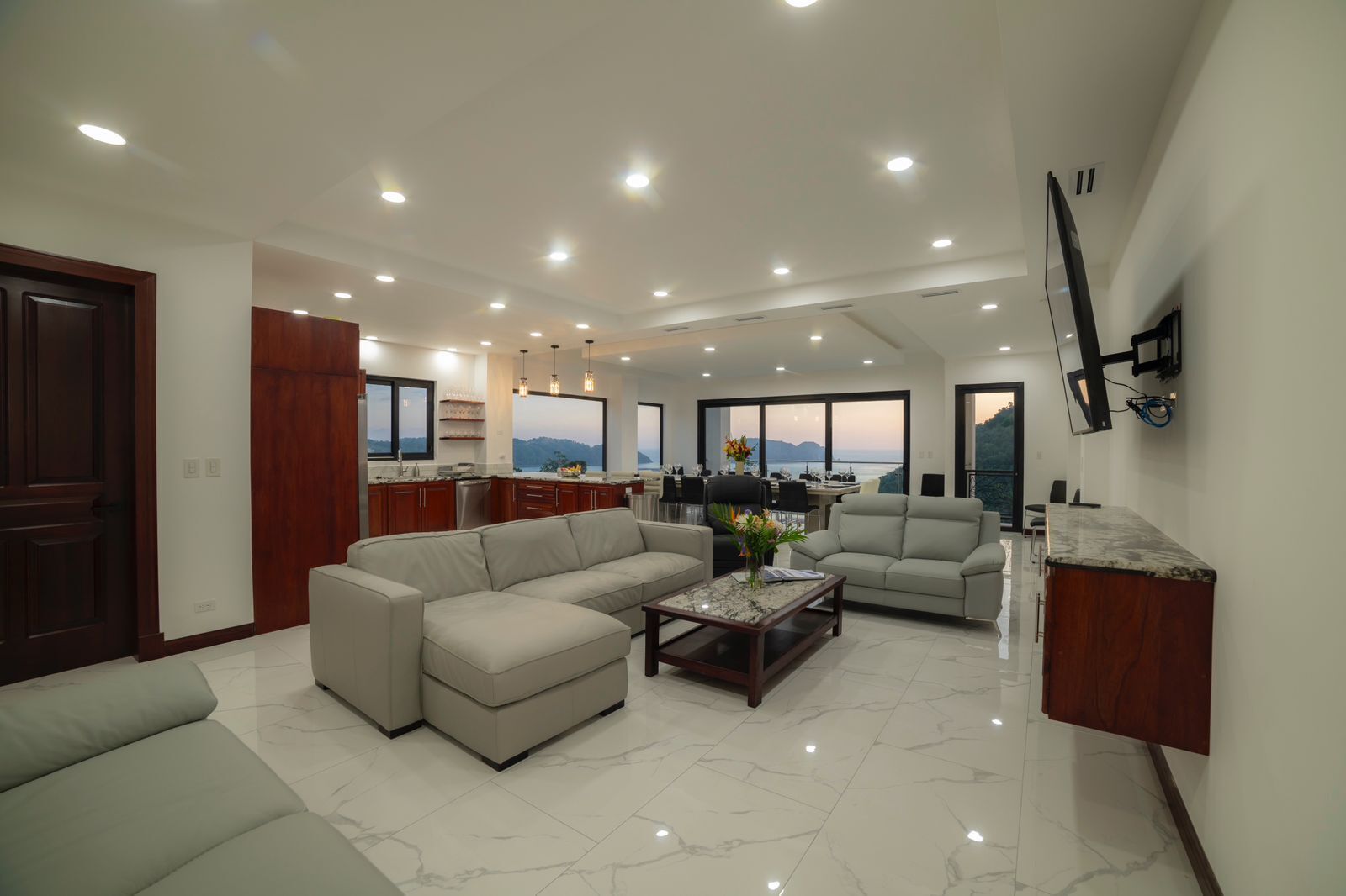 A spacious living area with a large sofa, a coffee table, and a dining area with a view.