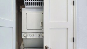 A laundry room with a washer and dryer, a basket, and a door.