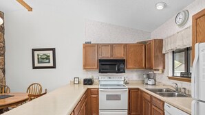 A compact kitchen with wooden cabinets, a microwave, an oven, a dishwasher, and a sink.