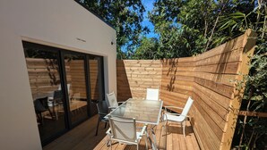 A wooden deck with a glass door leading to a patio area. - New 3-bedroom villa + SPA (Labenne)