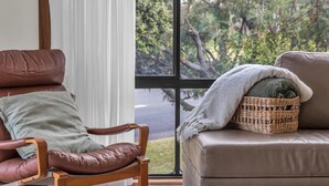 Ein Zimmer mit Ledersessel, gepolstertem Sofa und einem Korbwannenkorb mit Decke.