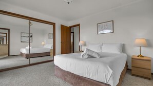 Ein Hotelzimmer mit einem großen Bett, einem Nachttisch, einem Spiegel und einem gerahmten Bild an der Wand.