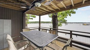 Een overdekt terras buiten, met een tafel en stoelen, met uitzicht op een waterpartij.