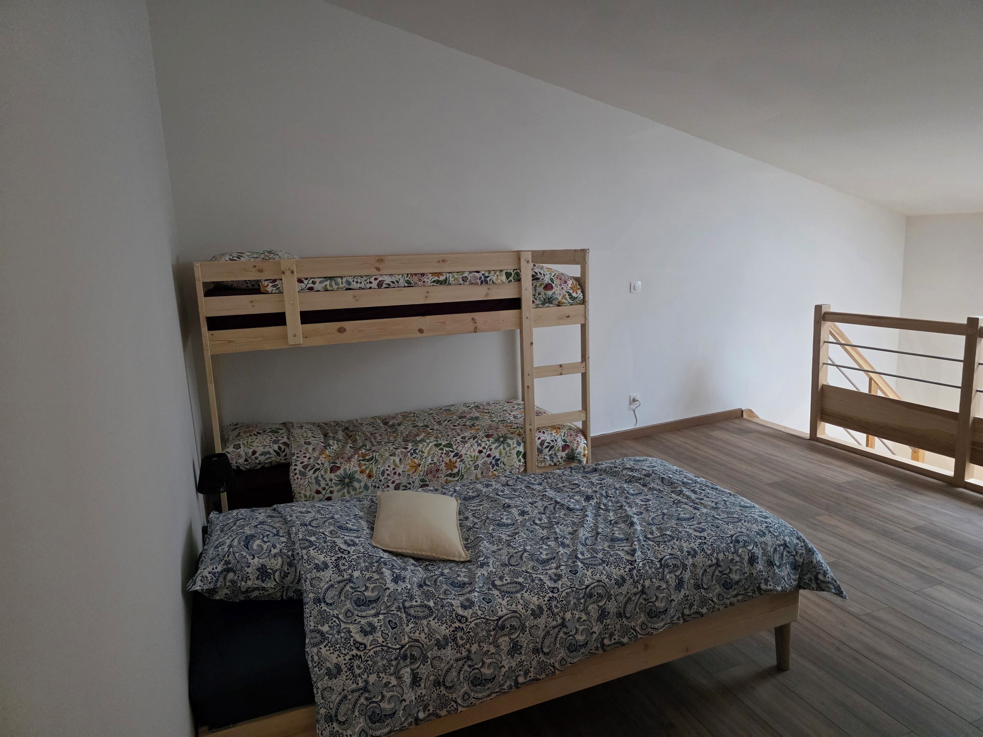Un lit superposé avec une couvre-lit à motifs floraux et un seul oreiller.