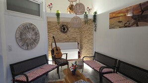 Un salon avec deux canapés noirs, une table basse en bois, une guitare et une cheminée.