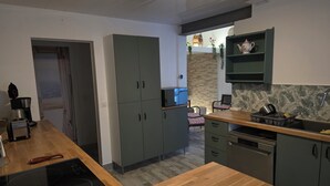 Une cuisine moderne avec des meubles gris, un plan de travail en bois et une cuisinière intégrée.