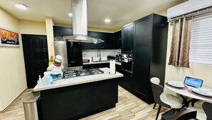 Una cocina moderna con una isla central, armarios negros y una zona de comedor con un ordenador portátil.