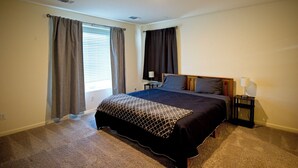 A bedroom with a large bed, two bedside tables, a nightstand, and a window with curtains. - Charming 3-bedroom house in nice Merced (Merced)