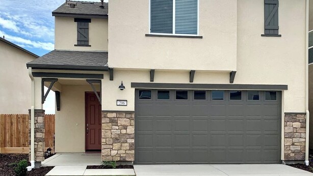 A two-story house with a garage, a front porch, and a stone foundation. - Charming 3-bedroom house in nice Merced (Merced)