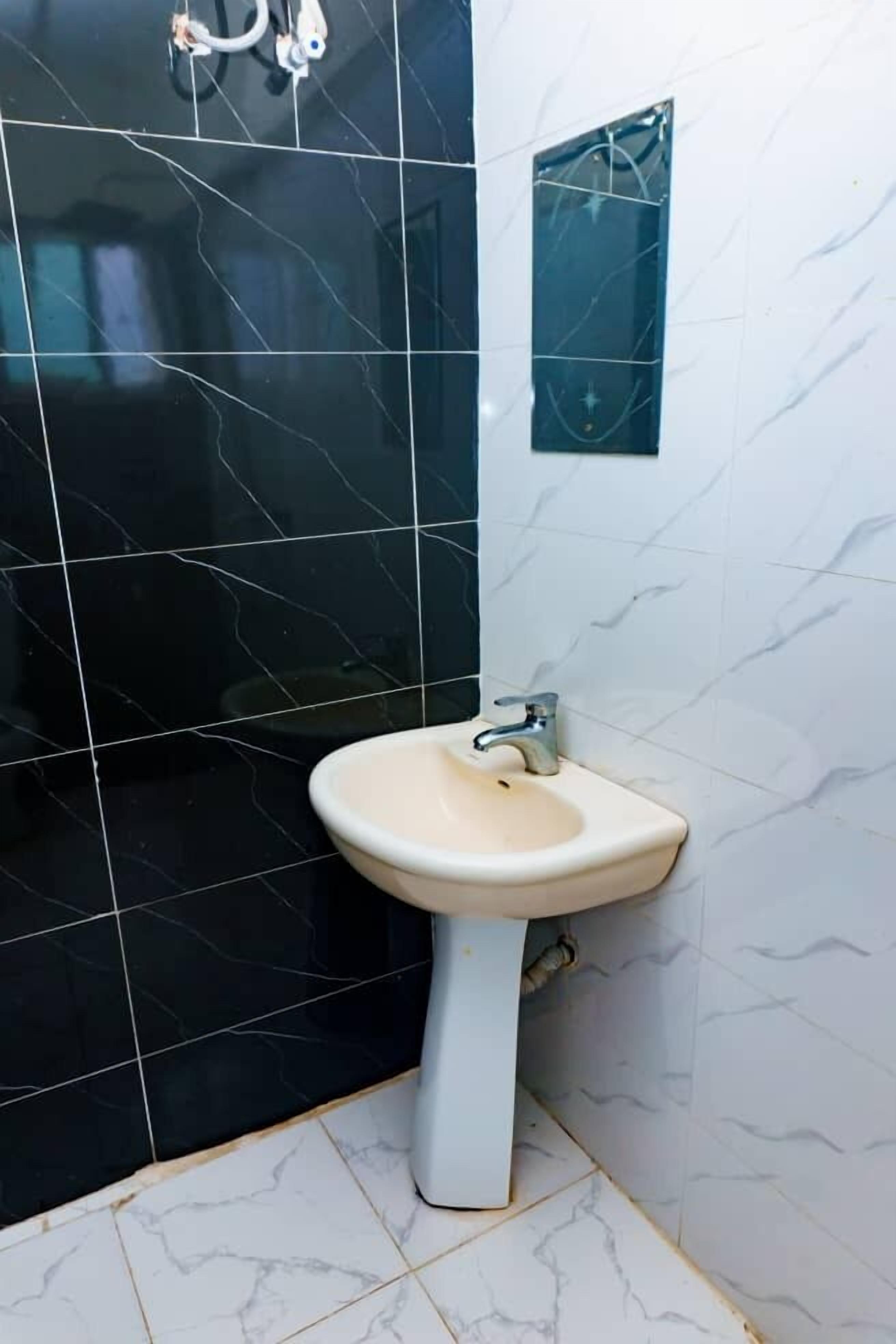 Ein Badezimmer mit Waschbecken, schwarz-weißen Fliesen und einem Spiegel.