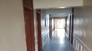 A long, narrow hallway with a polished tile floor and white walls. - Kenbrill Hyatt Hotel (Benin City)