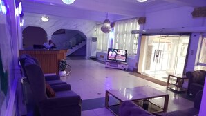 A spacious living area with a sofa, a coffee table, and a TV. There is a staircase leading to an upper level. - Kenbrill Hyatt Hotel (Benin City)