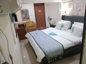 Una habitación de hotel con una cama, una silla, un escritorio y un televisor de pared.