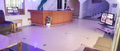 A lobby with a reception desk, seating area, and a staircase.
