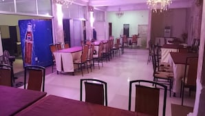 A dining area with multiple tables and chairs, chandeliers, and a large Pepsi refrigerator. - Kenbrill Hyatt Hotel (Benin City)