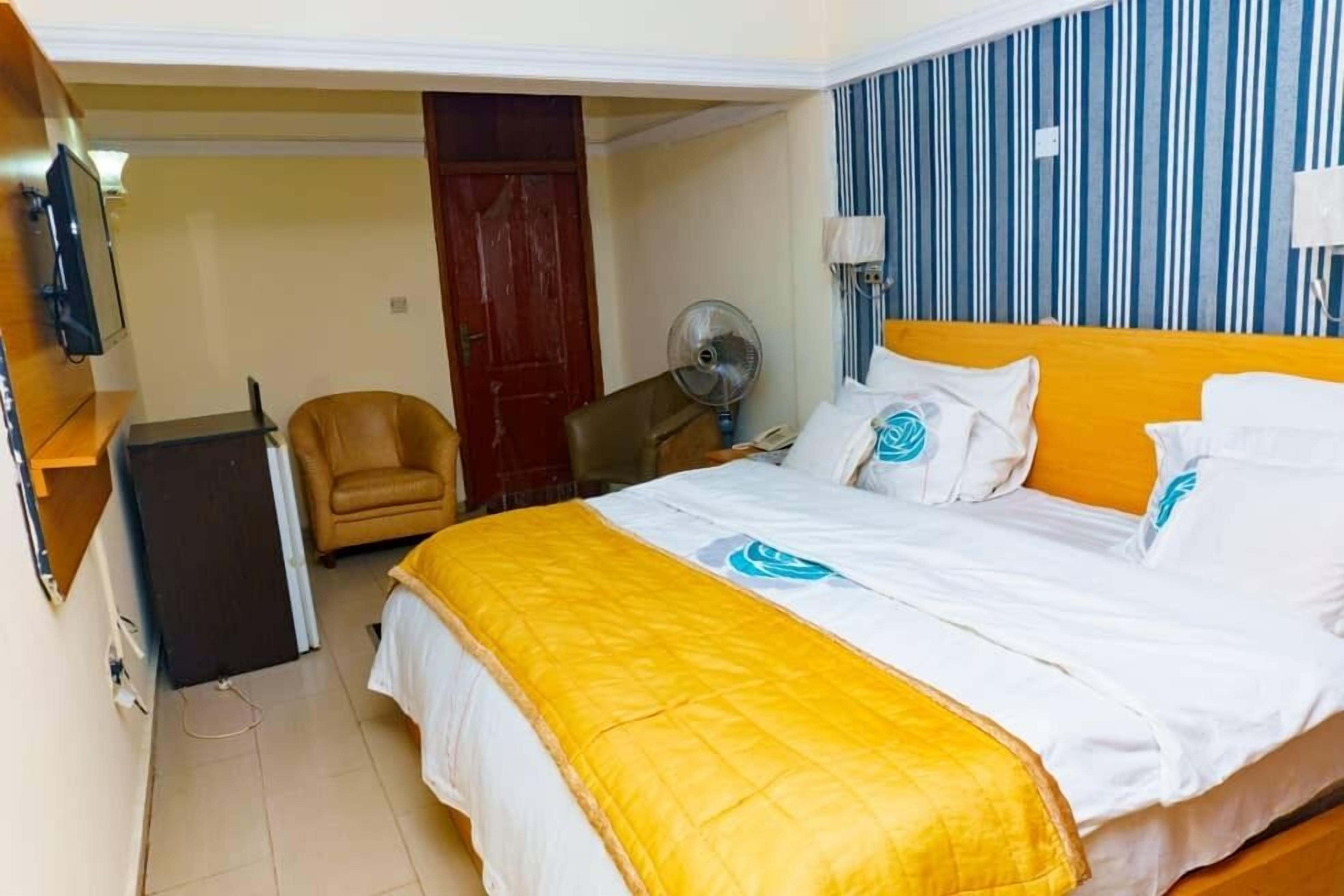 Une chambre d’hôtel avec un lit, une chaise, un bureau et un ventilateur.