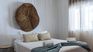 Una cama bien hecha con almohadas, una colcha y un adorno en la pared.